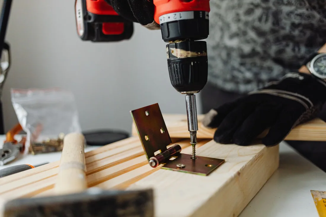 Close-up of a hinge being fastened into wood.