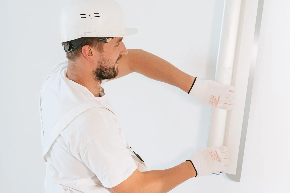 Worker installing drywall indoors.