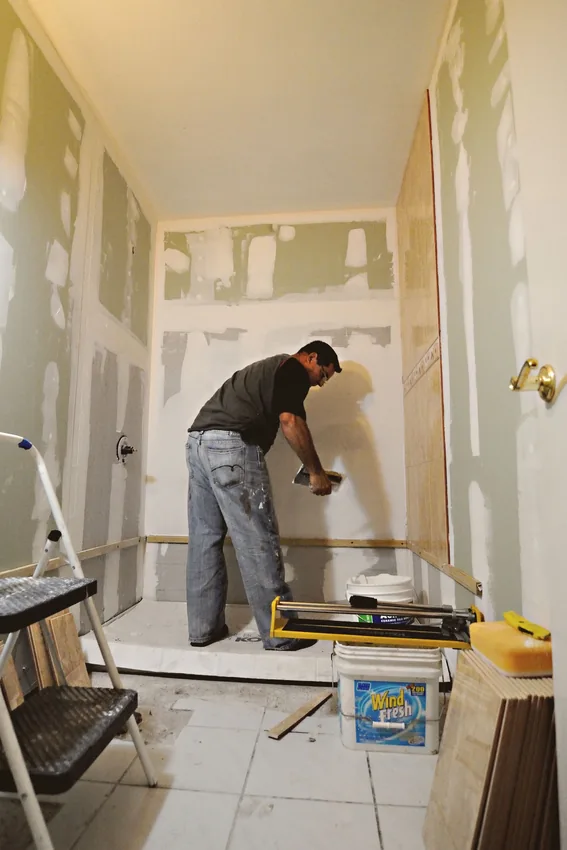 Worker applying drywall compound during wall repair.