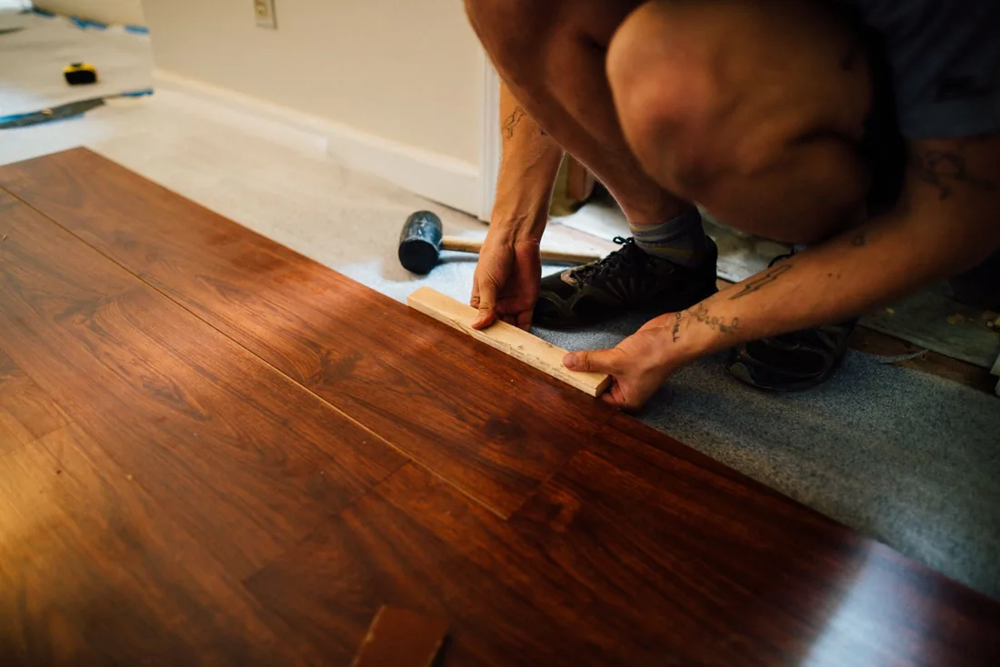 Worker laying laminate floor planks.