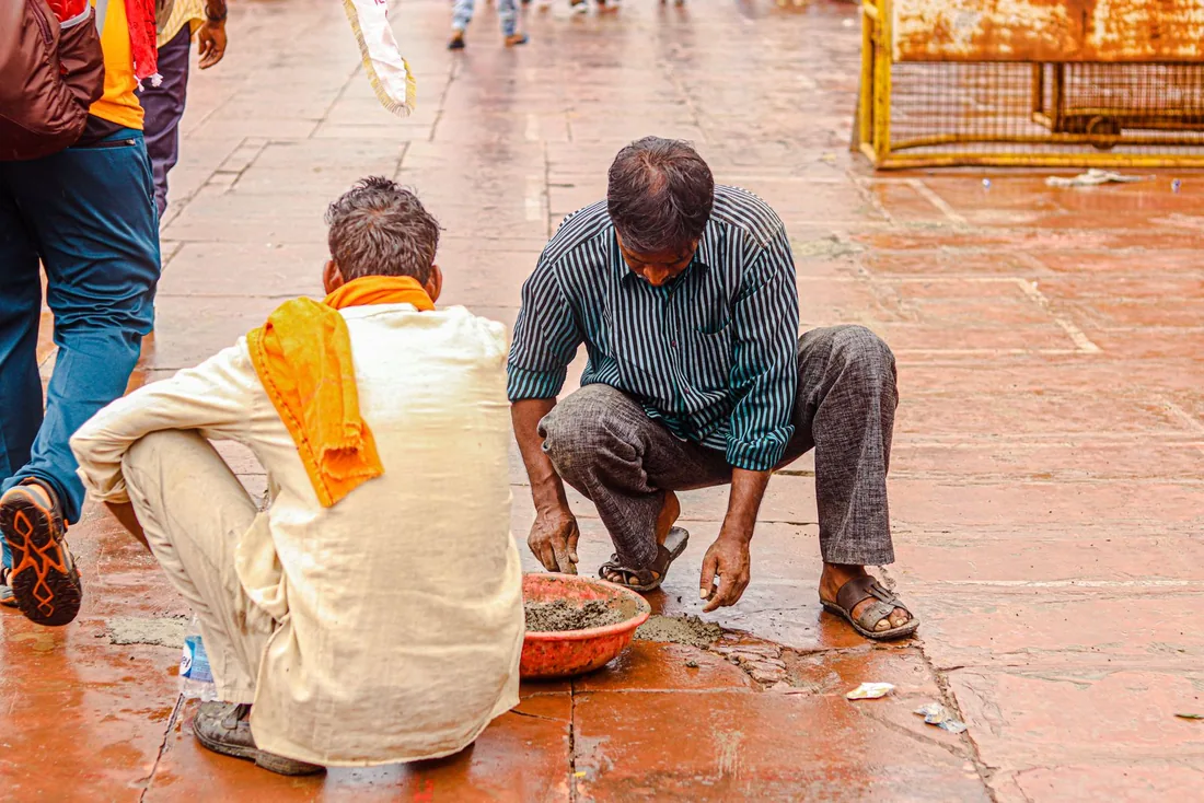 Workers repairing a tiled floor surface.