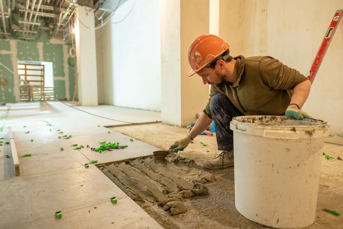 Worker laying tiles in an indoor renovation.