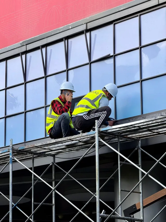 Workers installing replacement windows on a building.
